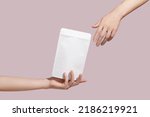 Female hand holds white cardboard packaging for tea, coffee, snack on pink background. Branding and packaging mockup. High quality photo