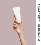 Small photo of Hand holding blank white plastic tube on pink background. Cosmetic beauty product branding mockup. Copy space. High quality photo