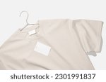 Beige t-shirt with blank clothing price tag or label mockup on a clothes rack. Ecology concept. Clothing sale concept