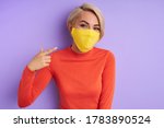Small photo of young caucasian woman propagandize protective medical masks, stand wearing yellow mask, prevents coronavirus infection. isolated purple background