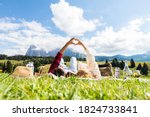 Romantic couple in love doing picnic visiting mountains alps. Boyfriend and girlfriend enjoying love doing heart shape with hands outdoor.