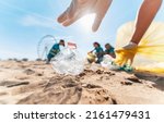 Small photo of Group of eco volunteers picking up plastic trash on the beach - Activist people collecting garbage protecting the planet - Ocean pollution, environmental conservation and ecology concept