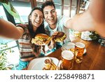 Happy couple taking selfie with smart mobile phone at burger pub restaurant - Young people having lunch break at cafe bar venue - Life style concept with guy and girl hanging out on weekend day 
