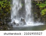 Close up view of low shutterspeed water falling on rocks in plunge pool of the Svartifoss waterfall in Skaftafell in Vatnajökull National Park, Iceland with a base of sharp basalt hexagonal columns