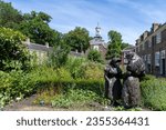 Small photo of Breda, the Netherlands-July 18, 2023; Statue of two beguines in the courtyard of the beguinage (Begijnhof) with herb garden and surrounded by 29 small houses