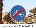 Small photo of End of cycle path sign. Blue round road sign with red strikethrough cross out line. Urban area, in Spain