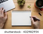 Person sketching or taking note down on blank open notebook with cup of fresh coffee on desk