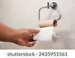 Hand pulling toilet paper roll...