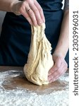 Small photo of Close-up of kneaded dough in female hands. The process of kneading the dough.