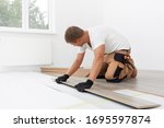 Male worker installing laminate flooring. Longitudinal lock joint - The sequence of technological methods for laying and installation of floating flooring - laminate - professional work
