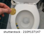 Small photo of man holds bitcoin over the toilet. Concept showing a misguided investment in cryptocurrencies