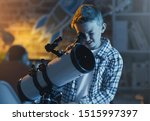 Small photo of Cute boy watching stars through a telescope at night in his bedroom, imagination and discovery concept