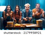 Cheerful group of friends playing video games together at home, leisure and entertainment concept