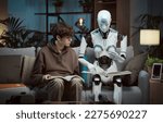 Small photo of Innovative AI robot tutor helping a teenage boy with homework, they are reading books together, human-robot interaction concept