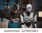 Smart teenager programming a humanoid AI robot at home using a digital tablet, science and technology concept