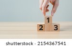 Small photo of Businessman's hand chooses number 1 on the podium with number 2, 3 of wooden building blocks. ranking and strategy concept. winners podium, Business hierarchy