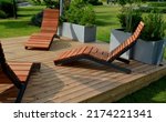 Small photo of rocking chair on the pavement under the trees in the square. wooden deck chairs made of tropical wood for one person in the park. They are comfortable made of brown planks, slats steel frames, pine