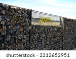Small photo of construction of a gabion retaining wall, as part of the fencing home coarser gravel filled poured between two wire slabs. stones peek between the meshes of the net