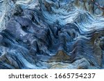 richly detailed rock with blue variants. stone full of curves and smooth cuts resulting from the erosive effect of sea. Close up rocks, texture dramatic and colorful erosional water formation. natural
