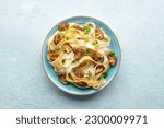 Mushroom pasta, pappardelle with cream sauce and parsley, overhead flat lay shot on a stone background