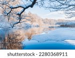 Small photo of A tranquil winter scene of a frozen river reflecting the icy blue sky, surrounded by snow-covered trees in Molndal, Sweden.