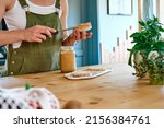 Small photo of Woman making healthy breakfast or brunch, spreading peanut butter on a puffed corn cakes. Protein diet healthy eating concept.