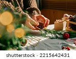 Woman making Christmas arrangement with fir branches and dried oranges. Female hands creating Christmas craft handmade decor. New year celebration. Winter holidays.