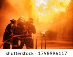 Firefighter using extinguisher or Twirl water fog type fire extinguisher to spray water from hose for fire fighting with fire flame on fuel and control fire for safety in plant of industrial area.