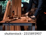 Small photo of Close-up the hand of carpenter craftsman making pool cue or snooker cue with a manual hand wood planer in carpentry workplace. Handmade craftsman concept. Focusing on hand wood planing.