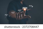 Small photo of Business plan and vision for 2024. Startup for business. Performance goals for growth ,Businessman uses his finger to kick the 2024 graph showing marketing strategies for the annual business plan.