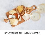 Cheese plate served with white wine, crackers and nuts, Top view. Assorted cheeses Camembert, Brie, Parmesan blue cheese, goat