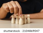 Small photo of Wooden figures human was chosen leadership of teamwork. man's hands are select wooden puppet to devise strategies for appointing leaders. leadership of teamwork concept.