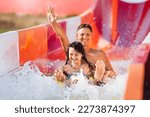 Happy family rushes down high slide on an inflatable circle in water park. Father and daughter in aquapark.