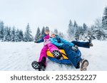 Smiling children ride down on inflatable tubing sleds. Inflatable sleds for active winter family recreation. Wide angle shooting.