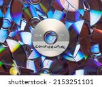 CD with confidential written on it, with shredded CD's and DVD's in the background.
