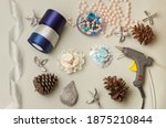 Needlework lessons.Tapes,cloth, glue gun.Hat hair clip.Crafts.DIY.
Shiny ribbon,cones,handcraft tool, ribbon beads on a gray background.Winter crafts. Quarantine session.Handmade.