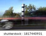 Small photo of Long exposure at a speed measuring device and a fast passing car in motion blur, automatic traffic monitoring with light radar and camera to punish speeding with fines or revocation of driving license