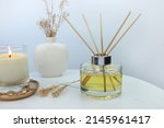 Small photo of luxury aromatic scent of reed diffuser glass bottle is used as room freshener on white marble table with scented candle in the bedroom to creat relax ambient with white cement wall background