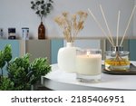Small photo of luxury lighting aromatic scented candle is on white metal table with ceramic vase and reed diffuser to creat relax ambient in the bedroom with background of nice bedroom and curtain on Valentine day