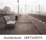 Lonely moody scene with a train station or railway platform on a foggy morning.