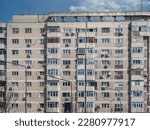 Small photo of Worn out apartment building from the communist era against blue sky in Bucharest Romania. Ugly traditional communist housing ensemble