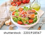 Healthy food. Lettuce salad with red fish, raw vegetables and olive oil. Red fish sandwich with rye bread, poppy seeds and mustard sauce on blue background