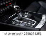 Small photo of Automatic gearbox handle, multimedia dashboard and leather interior of high-end modern car. Close up of deluxe vehicle attributes.