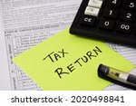 Sticky note with the handwritten text TAX RETURN placed on Income Tax Return filing form. Selective focus on the text. 