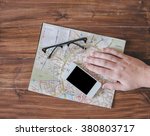 Hand, map, glasses and phone on the wood table