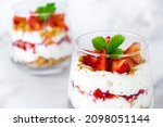 Small photo of Strawberry trifle dessert with custard, cake crumb and fresh strawberry in glass on marble. Recipe of simple layered dessert with fresh berry and jam. Lactose free vegan dessert parfait.
