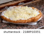 Small photo of Tasty Langos - a typical Hungarian street food, deep fried flatbread topped with sour cream, grated cheese placed on a run down counter at a beach buffet, traditional Hungarian cuisine