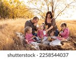 Small photo of Young family with triplet girls on picnic, eco-friendly paper tubes, biodegradable materials.