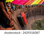 Small photo of Bogura, Bangladesh - May 15, 2022 - Daredevil motorcyclists ride around a steep 'wall of death' at 50 miles an hour with pillion behind