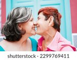 Senior gay lesbian couple kissing outside - LGBTQ aged tourists having tender moment during summer vacation